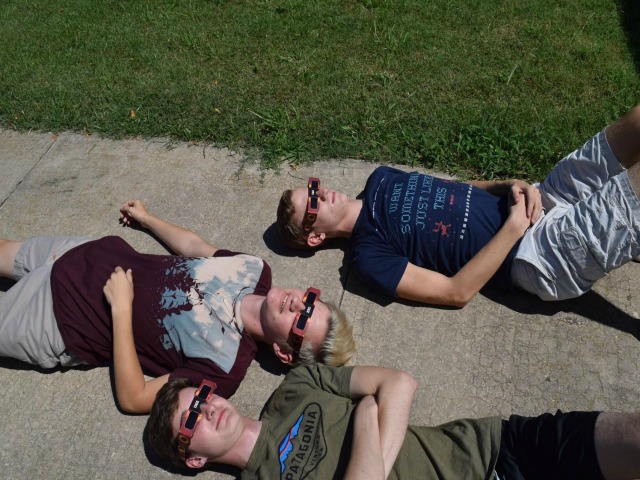 William Pottebaum, Bryan Moses, and Westin Williams watch the eclipse. They relaxed on the sidewalk and enjoyed their front row seats.