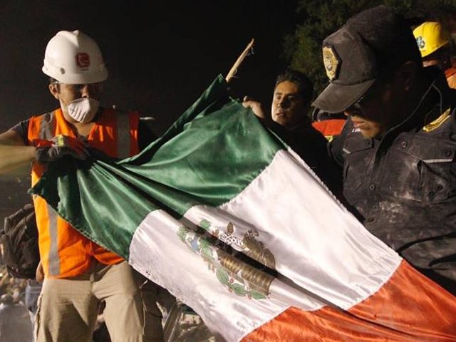 Mexican Authorities and rescuers pull the Mexican flag out of the rubble