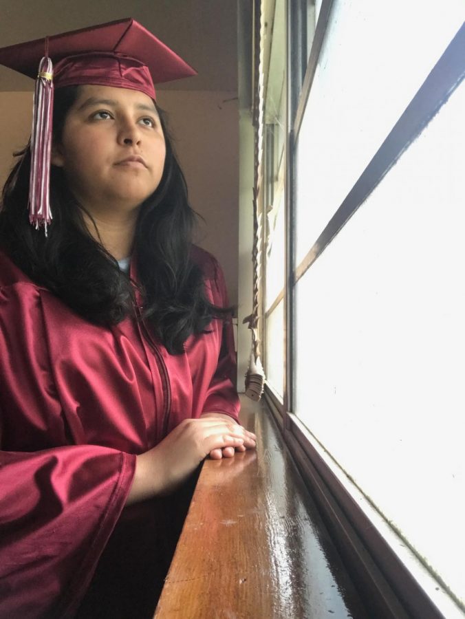 Using a timer, senior Karla Charqueno captures a photo of herself in her cap and gown. Charqueno imagined a very different end to her senior year than spending it in quarantine.